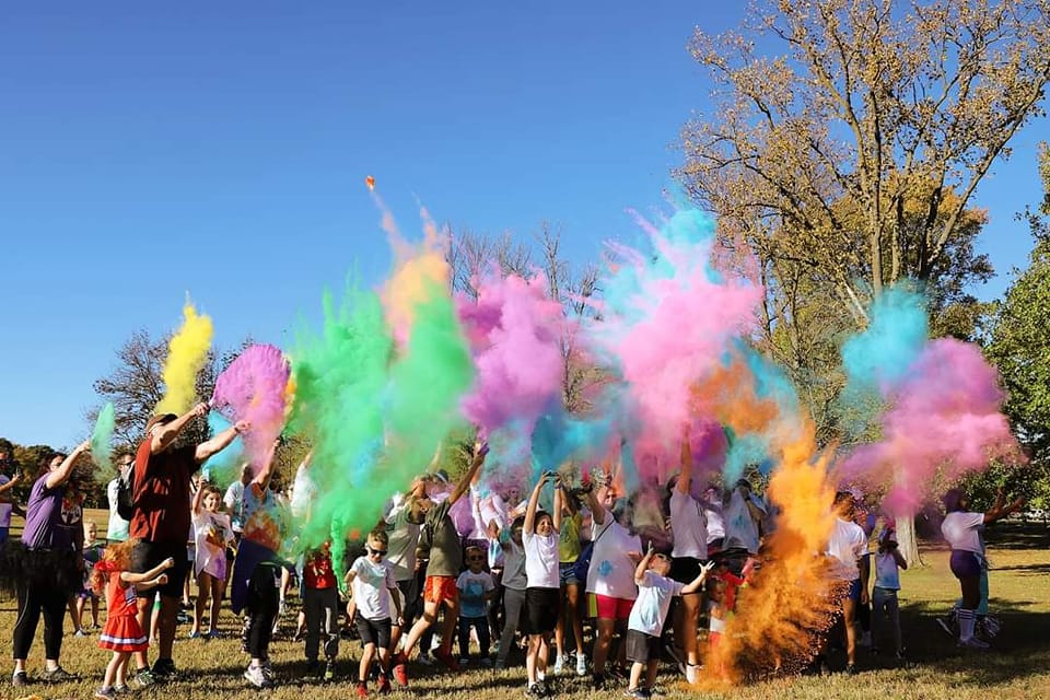Group of people throwing color powder in the air at the Uplift Color Run